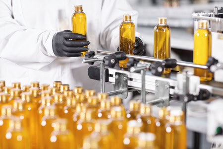 person manually operating a cosmetic packaging machine for liquids